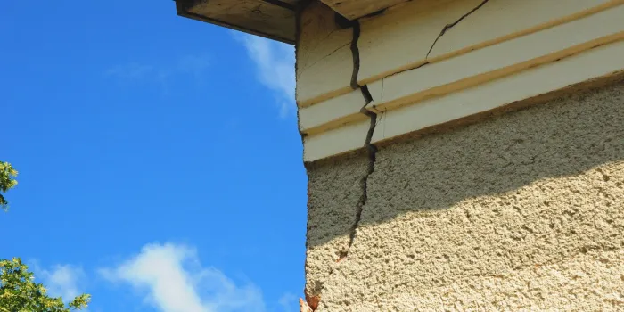 architecture detail of damaged house corner dilapidated old building facade wall over blue sky background private abandoned home fall to ruin exterior house