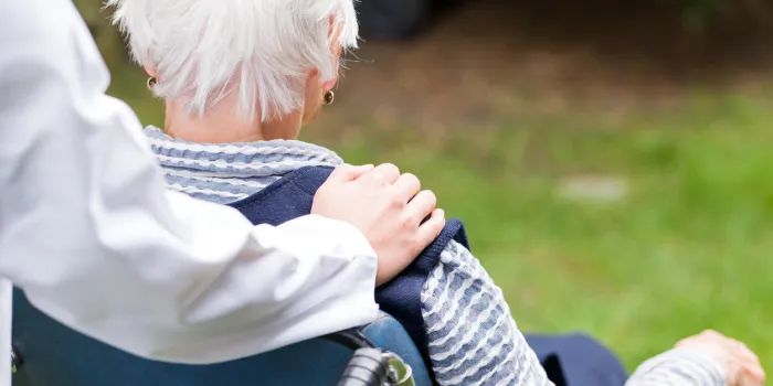 photo of young carer pushing the elderly woman in wheelchair